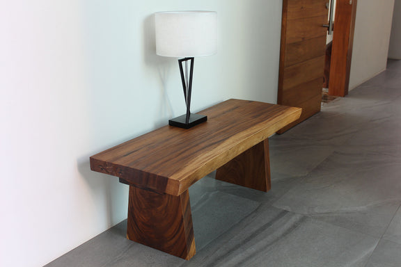 Haussmann Natural Edge solid wood bench in Walnut finish in an entryway with a lamp on top