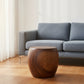 Haussmann MMP pouf stool accent table, 20 in dia x 18 in H walnut oil, in a living room in front of a blue-grey sofa